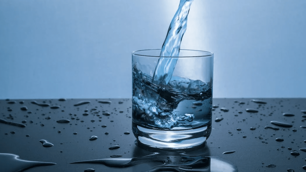 water being poured into a glass on blue background