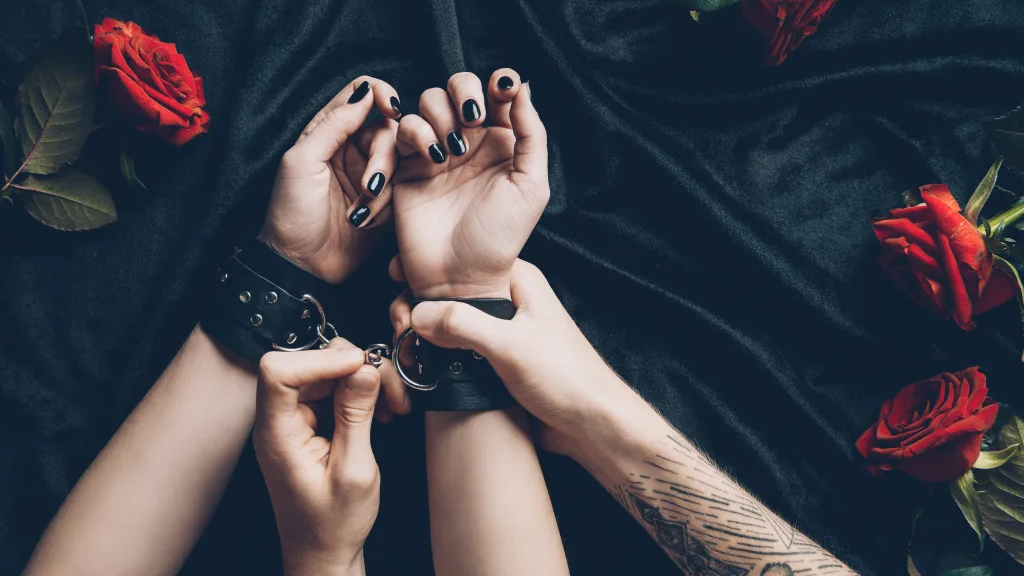 woman's hands in leather bdsm cuffs held by man