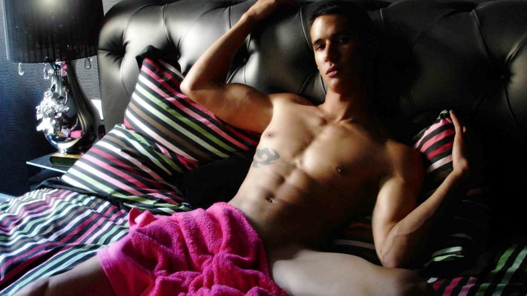 male cam model in bed wearing a pink towel